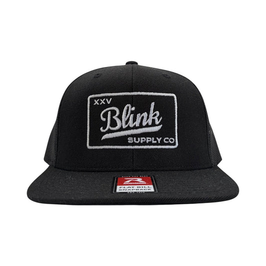 Blink Supply Co XXV flat bill trucker cap in black with white premium embroidery on a six-panel snapback design